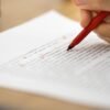 une personne en train d'annoter un synopsis avec un stylo rouge