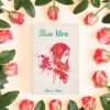 La couverture entourée de roses rouge pale La couverture présente un fond blanc texturé. Au centre un visage de femme voilée dans des tons rouges. En haut un titre en vert dans une police travaillée. En bas le nom de l'auteurice en vert dans la même police.